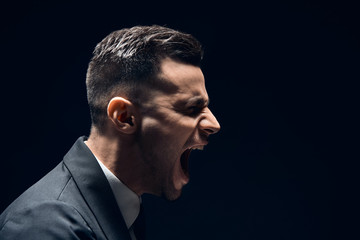 Profile view of angry disappointment man shouting with copy space isolated on dark background