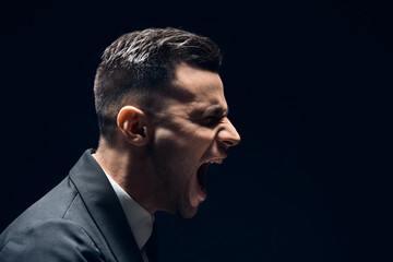 Obraz premium Profile view of angry disappointment man shouting with copy space isolated on dark background
