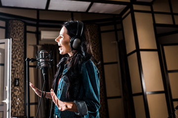 Fototapeta na wymiar beautiful inspired woman singing near microphone in recording studio