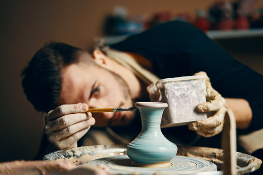 Man painting handmade pottery at ceramic workshop