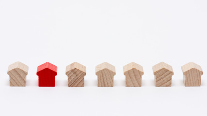 Rangée de petites maisons en bois, une d'entre elles peinte en rouge, fond blanc