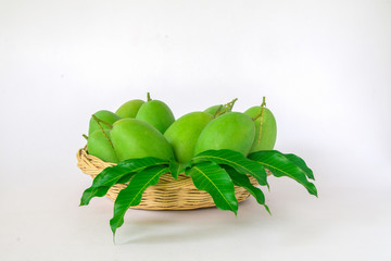 Green mango is in a wooden basket in a white background.