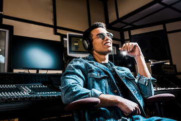 Fototapeta na wymiar good-looking, mixed race sound producer in headphones listening music in recording studio