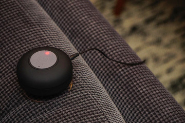 Small bluetooth speaker being charged on the couch close up view