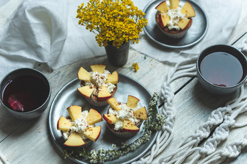 sweet muffins with yoghurt and apples and tea in silver metal dishes on a light, rustic wooden table