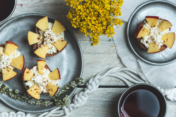 sweet muffins with yoghurt and apples and tea in silver metal dishes on a light, rustic wooden table