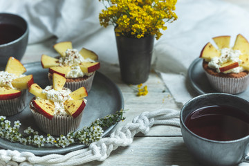 sweet muffins with yoghurt and apples and tea in silver metal dishes on a light, rustic wooden table