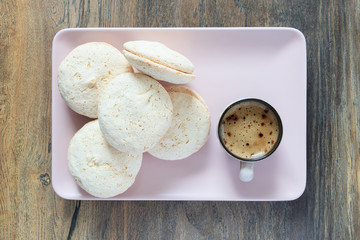Cake macaroon cup of coffee on a rectangular plate on the background of a desk