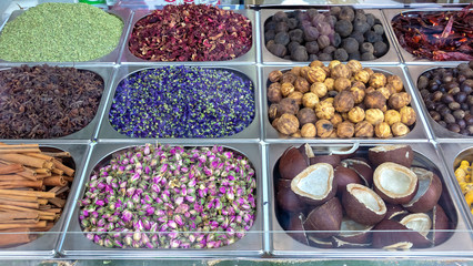 Spice and dried herb counter on the old market, Dubai, UAE. Rose, dried lemon, star anise, mint, coconut halves and hibiscus. Selective focus.