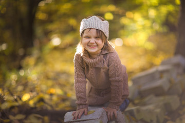 Fun girl playing in autumn park, knitted sweater