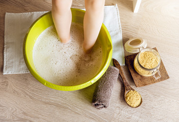 Child taking a healing warming foot bath with mustard powder, adding mustard powder to foot bath...