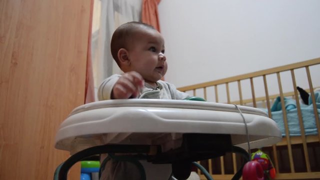 low angle shot Cute six months old baby boy in the walker early development, learning how to walk.