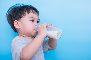 Asian little child boy about 2 year drinking milk from bottle glass itself