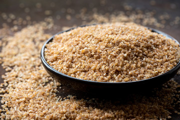 Dry crushed spelt in a bowl on a dark background.