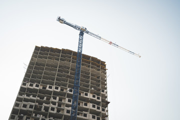 Modern building under construction with crane
From below of constructing building with high crane under clear sky