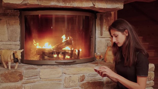 Woman Relaxing by the Fire Answers a Phone Call.