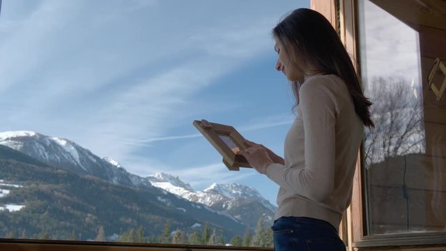 Woman Connects with Photo of Loved One in Alpine Scene.