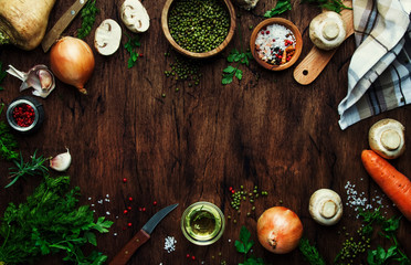Food cooking frame background. Ingredients for prepare green lentils with vegetables, spices and herbs, wooden kitchen table background, place for text. Vegan or vegetarian food oncept
