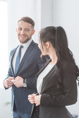 cheerful bearded man looking at brunette woman while touching formal wear