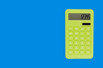 One modern green plastic calculator on blue office table. Top view. Business or education concept. Copy space for your text