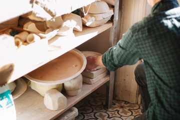 Man potter looking for ware for a work. Young man potter in his workshop. Handsome man work