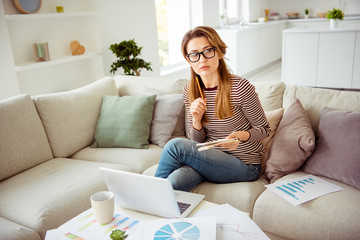 Learn education university student . Photo concentrated beautiful trendy lady long wavy curly hair plan solve graphs creative report clever sit divan eyeglasses eyewear striped shirt jeans room