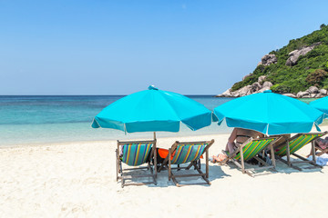 Row of blue parasols with wooden beach chairs on tropical sandy beach in sunny day at Koh Nang Yuan Island Surat Thani, Thailand     
