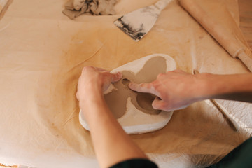 Hands of a potter creating element of decor using a clay. Close up of male hand's