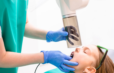 Obraz na płótnie Canvas Elementary age girl receiving dental radiography or X-Ray in pediatric dental clinic