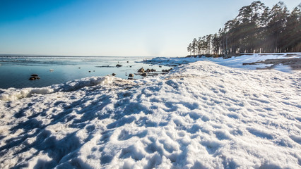 Snow pile, hill. Large snow drift isolated on a blue sky background,  outdoor view of ice blocks at frozen finland lake in winter