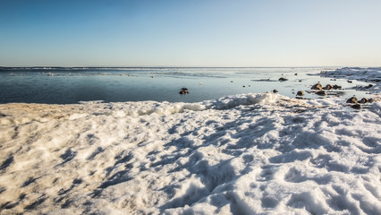 Obraz premium Snow pile, hill. Large snow drift isolated on a blue sky background, outdoor view of ice blocks at frozen finland lake in winter