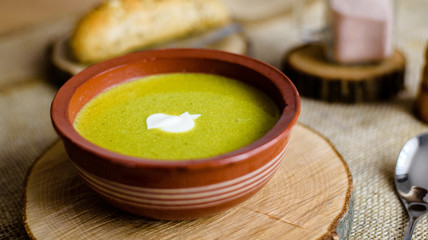 Green vegetable broccoli organic soup in ceramic bowl. Wooden plate with delicious croutons bread. Vegan, organic diet dish.