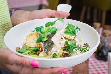 Woman hands holds big white plate with fresh salad close-up photo