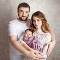 Woman and man holding a newborn. Mom, dad and baby.  Portrait of  smiling family with newborn on the hands. Happy family concept. Copy space