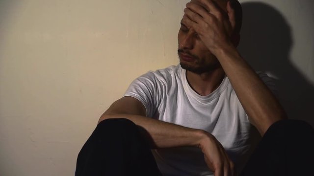 Depressed man, Lonely and depressed addict man sitting alone on the floor of his dark home feeling miserable and anxious dark footage social documentary health care concept