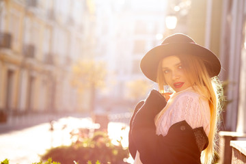 Amazing blonde woman wearing sweater and hat posing at the old street. Empty space