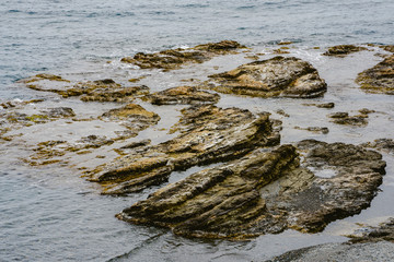 Sea rocks flooded by water on a cloudy winter day.