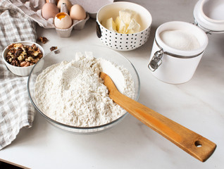 Ingredients for baking cake. Eggs, flour, sugar and whisk, butter nuts.