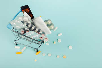 Shopping cart loaded with pills on a blue background. The concept of medicine and the sale of drugs. Copy space.
