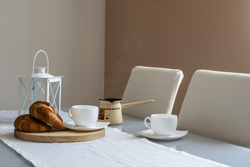 Minimalistic style interior. Cozy romantic breakfast for couple with hot coffee and fresh aromatic croissants.