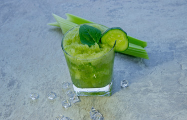 Nutritious celery cocktail for weight loss and maintaining a healthy lifestyle. In cocktail added cucumber and green leaf. There are also a few celery stalks and pieces of ice.