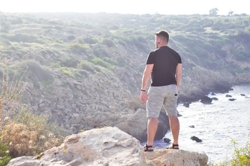 Hiker young man looking at the mountains in summer and enjoying view of nature.  Cyprus. Travelling and outdoor lifestyle concept. Copyplace, place for text