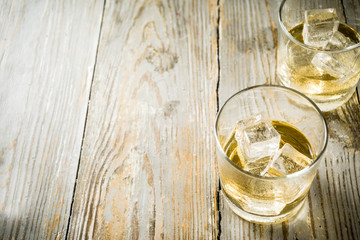 Amber Whiskey on the Rocks, alcohol drink in short glass, wooden background copy space