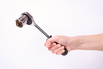 Ratchet wrench in a hand of the girl. Symbol of hard work, feminism and labor day. Isolate on white background.