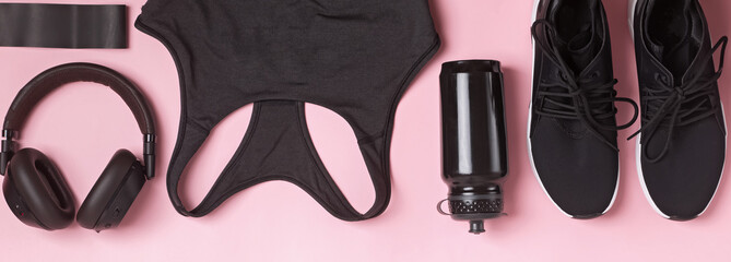 Black color fitness accessories set on pink background.