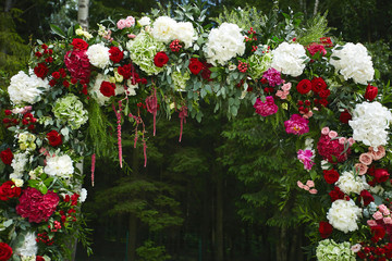 Round wedding floral arch from colorful fresh flowers outdoors before the wedding ceremony -...