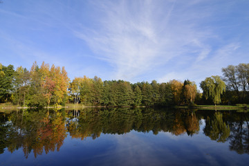 Fototapeta na wymiar Lake in the forest in autumnal colors and blue sky
