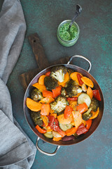 Pan of roasted different vegetables. Zucchini, sweet potatoes, carrots, broccoli, red bell vegetables. Dark green background, copy space