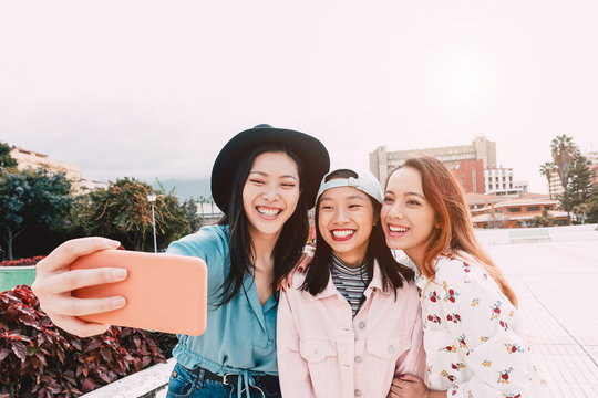 Happy Asian Girls Taking Selfie With Mobile Smartphone Outdoor - Young Trendy Teenager Having Fun With New Technology App - People, Social, Media, Friendship, Tech And Youth Lifestyle People Concept