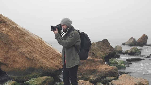 Young photographer taking photos of ocean cliff with DSLR camera